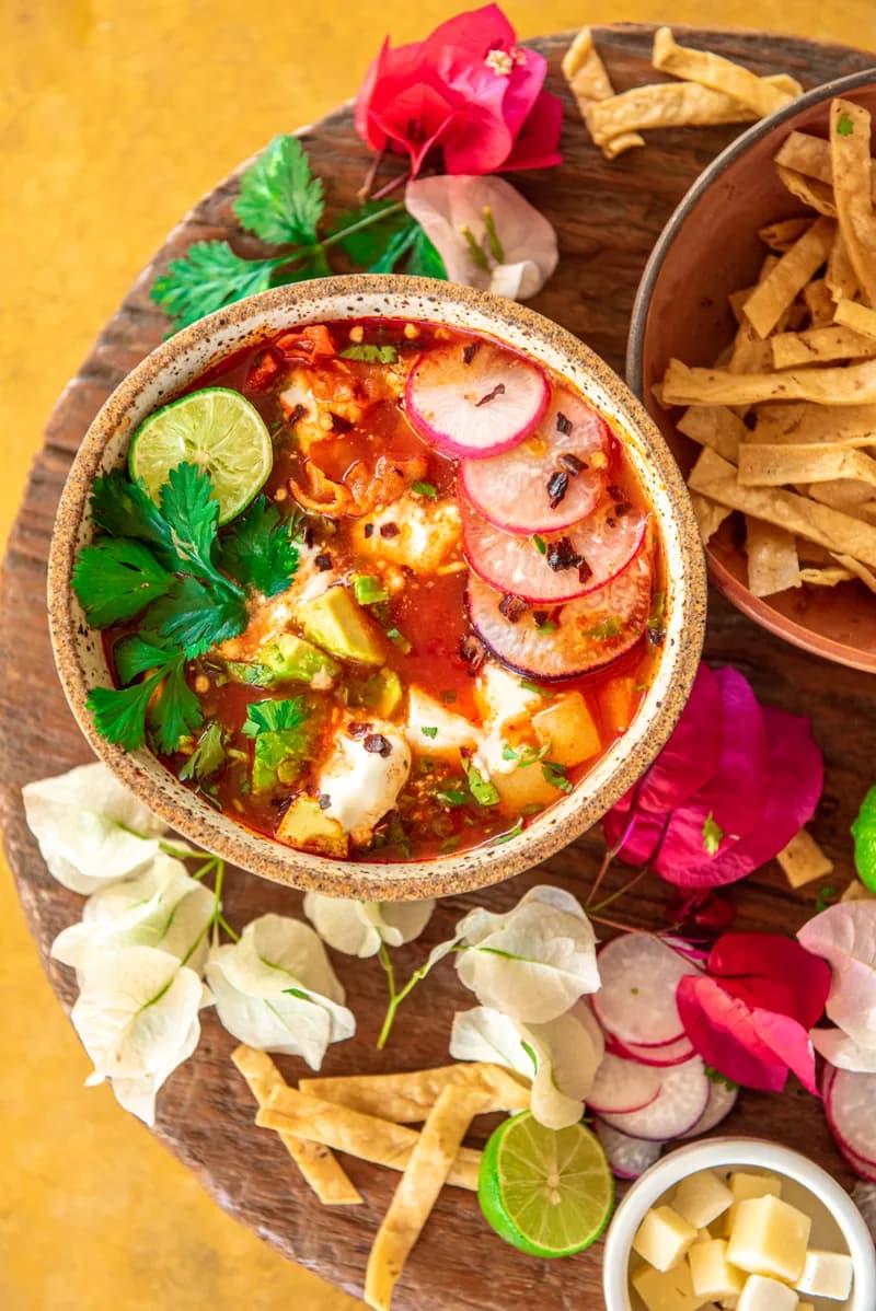A bowl of tortilla soup with lime and radish