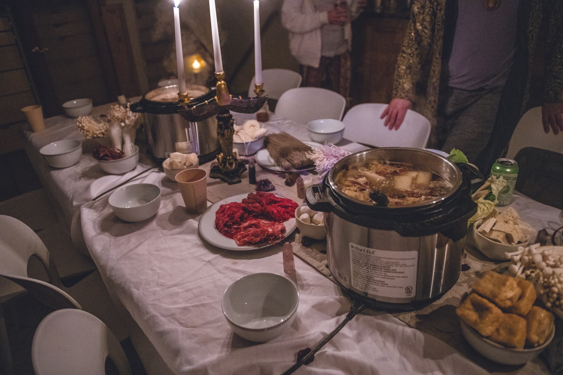 A table set with a pot of soup and a candle