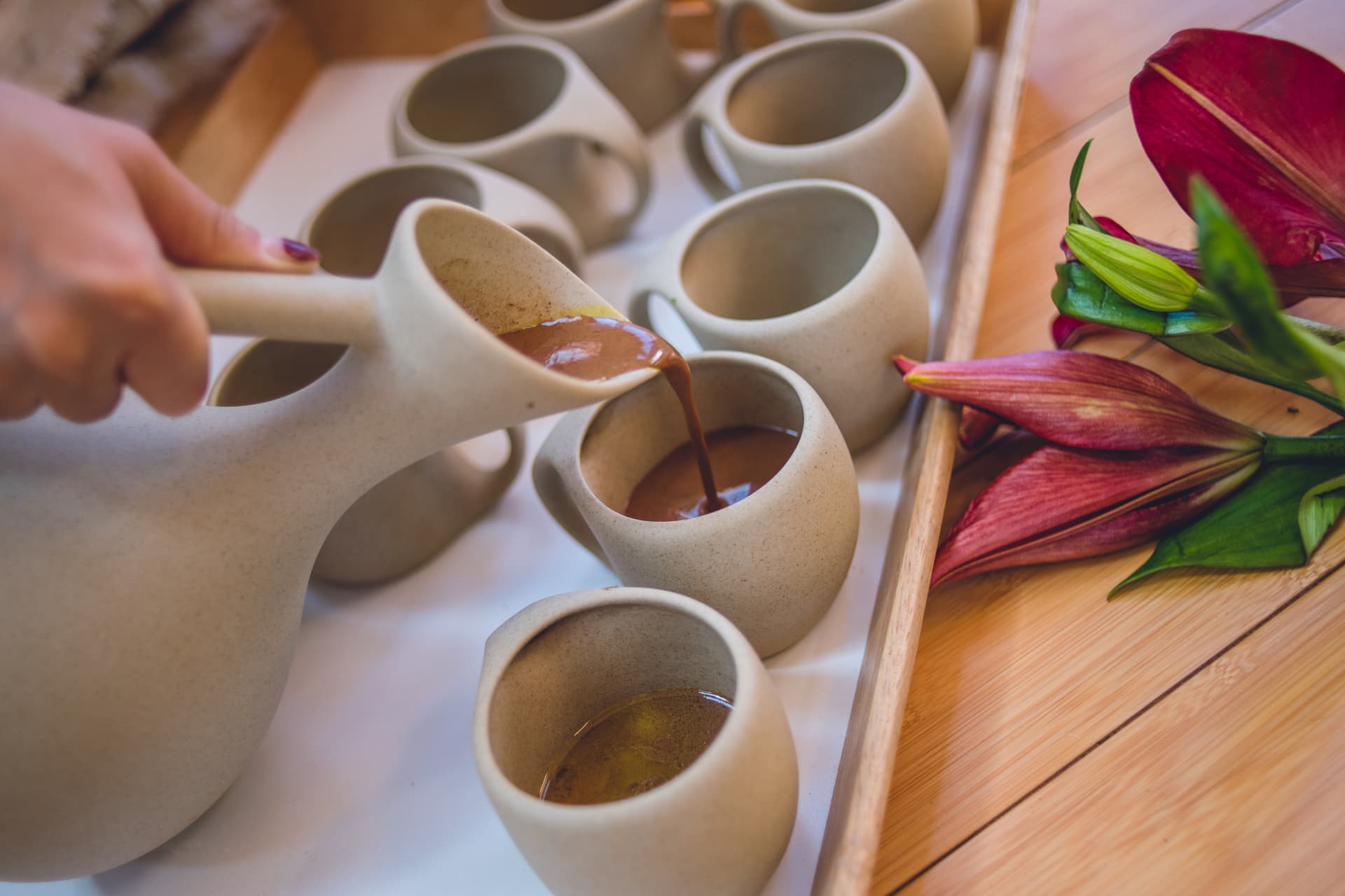 A hand pouring a ceremonial drink into a ceramic cup